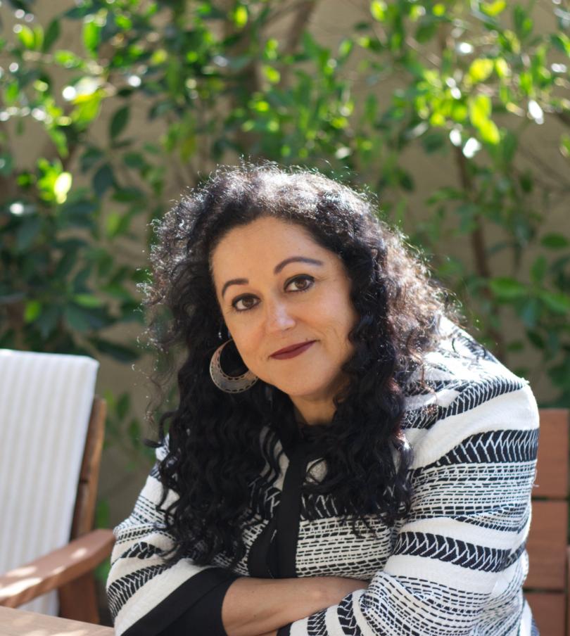 Photo of smiling woman with curly hair in a black and white striped top